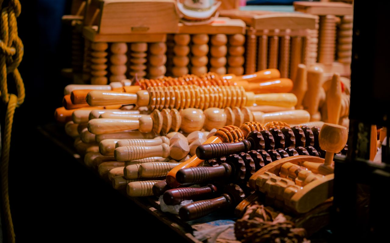 A variety of wooden massage tools neatly arranged in warm lighting, showcasing craftsmanship.
